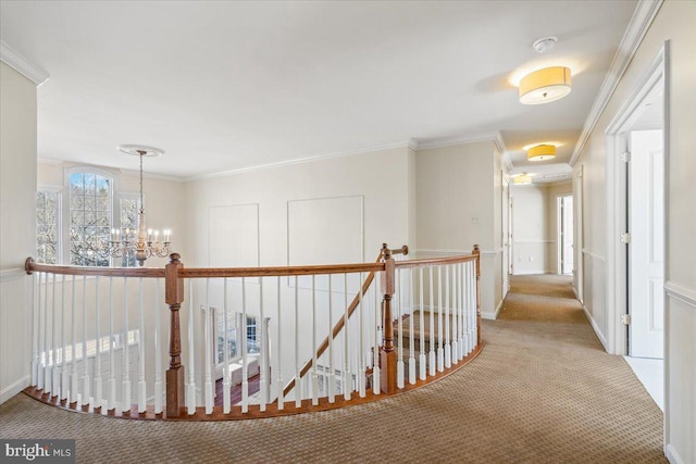 hall featuring carpet floors, a chandelier, ornamental molding, and an upstairs landing