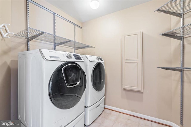 laundry area with laundry area, washing machine and dryer, and baseboards