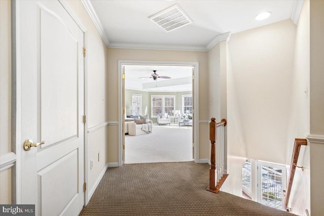 corridor with carpet flooring, visible vents, an upstairs landing, baseboards, and ornamental molding