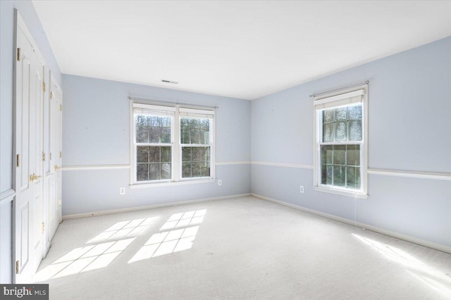 carpeted empty room with baseboards, visible vents, and a healthy amount of sunlight