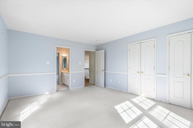 unfurnished bedroom featuring ensuite bathroom, carpet, and baseboards