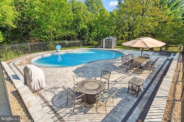 view of pool with an outbuilding, fence, a fenced in pool, a storage unit, and a patio area