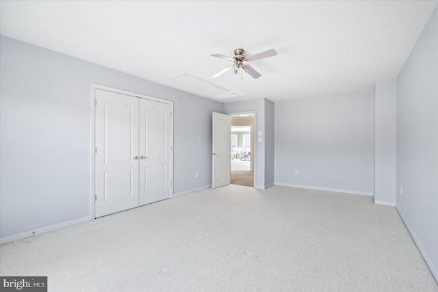 unfurnished bedroom featuring attic access, baseboards, ceiling fan, carpet, and a closet