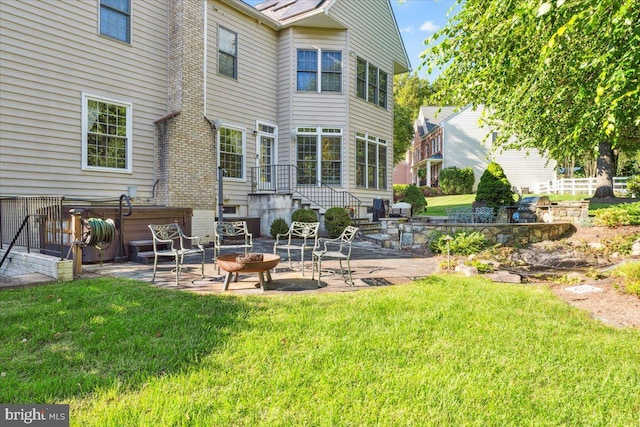 rear view of house with an outdoor fire pit, a patio area, and a yard