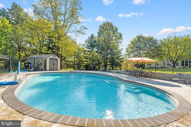 view of pool with a fenced in pool, an outbuilding, fence, a patio area, and a shed