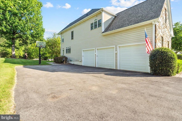 view of property exterior featuring roof with shingles, driveway, an attached garage, and a lawn