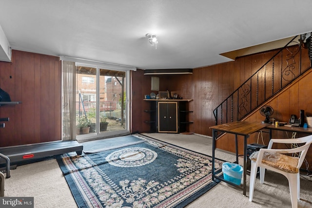 interior space featuring carpet floors, wood walls, and stairs