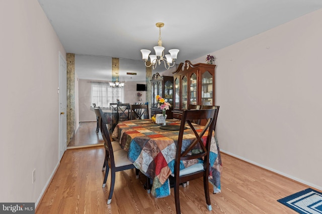 dining area featuring baseboards, wood finished floors, and an inviting chandelier