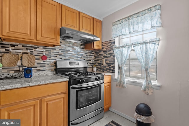 kitchen with tasteful backsplash, a healthy amount of sunlight, stainless steel gas stove, and under cabinet range hood