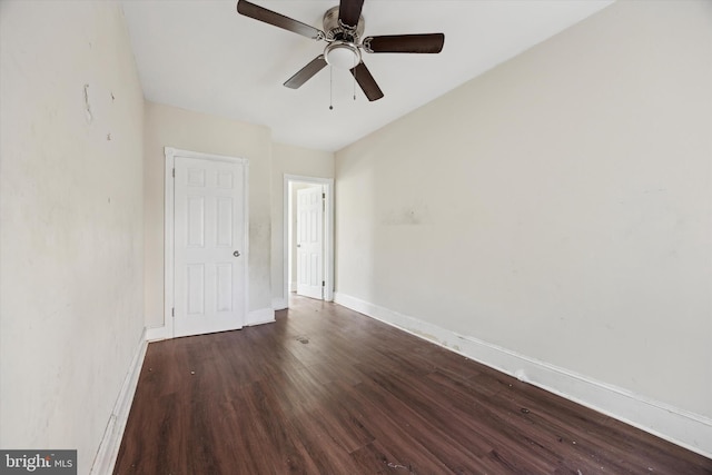 spare room featuring dark wood-type flooring, ceiling fan, and baseboards