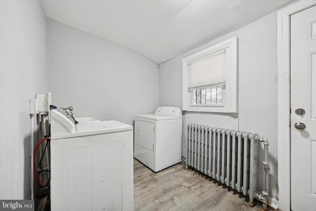 washroom featuring light wood-type flooring, washer and dryer, laundry area, and radiator heating unit