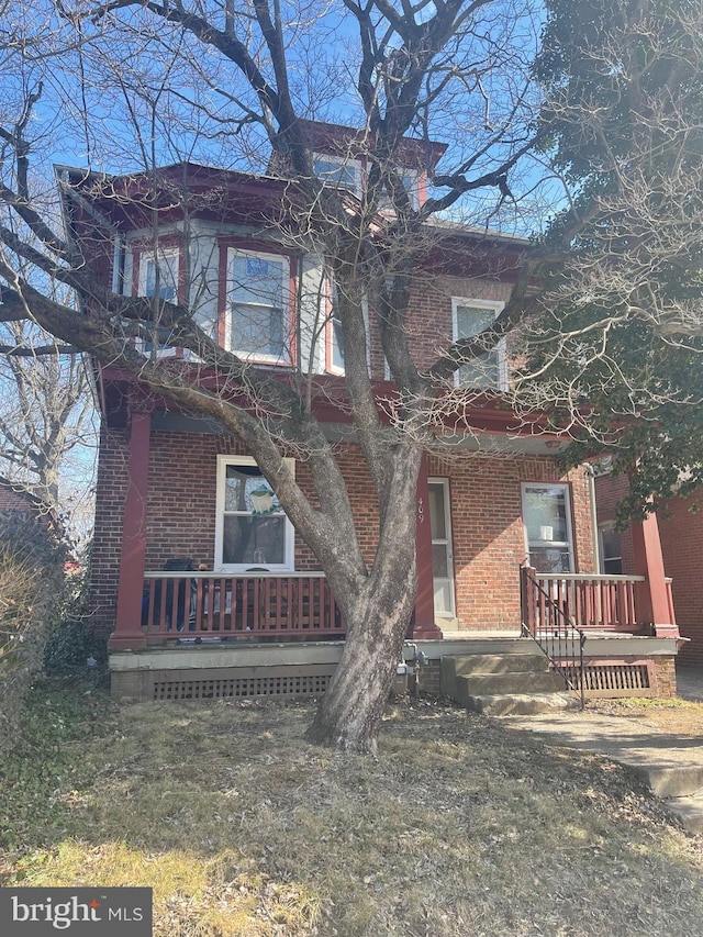 exterior space with a front yard, covered porch, and brick siding