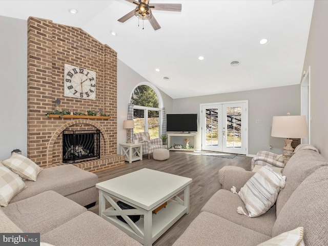 living room with visible vents, wood finished floors, french doors, a brick fireplace, and recessed lighting