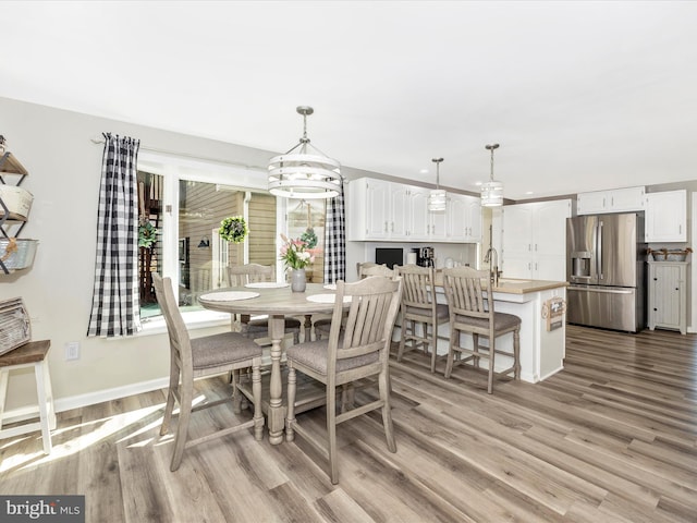 dining area with baseboards, a notable chandelier, and light wood finished floors