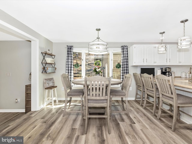 dining space featuring light wood-style floors and baseboards