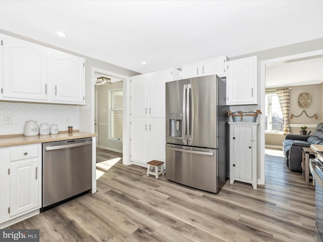 kitchen featuring stainless steel appliances, white cabinets, and light wood-style floors