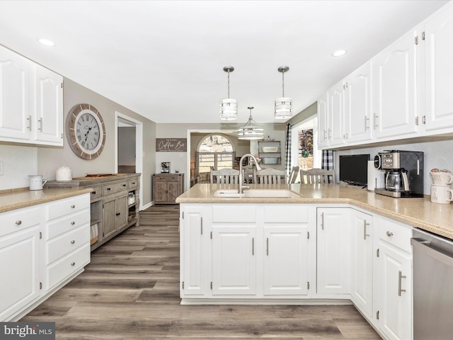 kitchen with tasteful backsplash, a sink, wood finished floors, dishwasher, and a peninsula