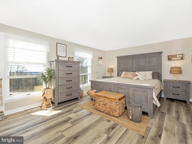 bedroom with baseboards, visible vents, and light wood-style floors