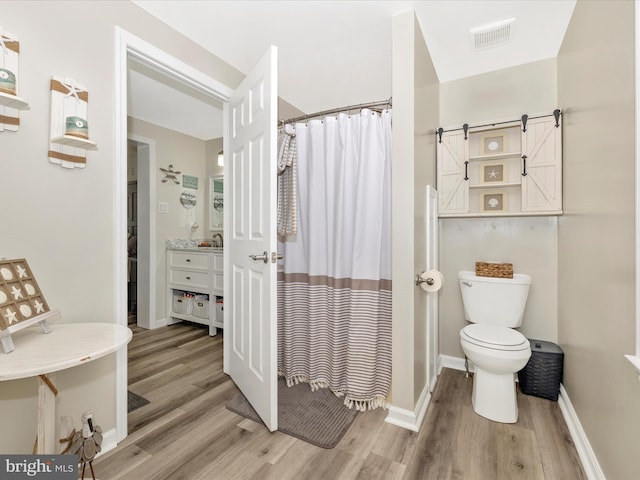 bathroom with visible vents, toilet, a shower with shower curtain, wood finished floors, and baseboards