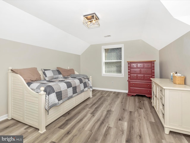 bedroom featuring vaulted ceiling, visible vents, light wood-style flooring, and baseboards