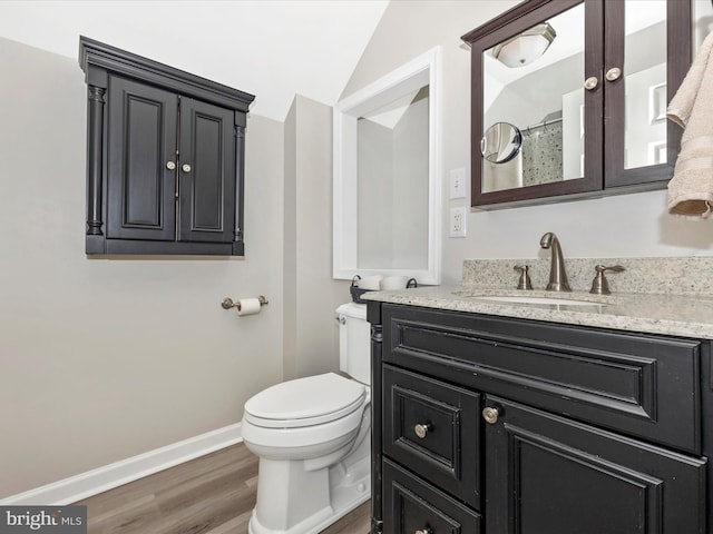 bathroom featuring baseboards, toilet, lofted ceiling, wood finished floors, and vanity