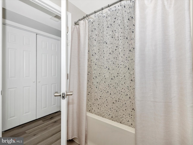 full bathroom featuring shower / bath combo and wood finished floors