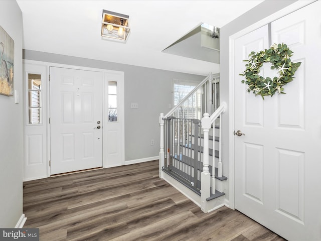 entrance foyer with dark wood-style flooring, baseboards, and stairs