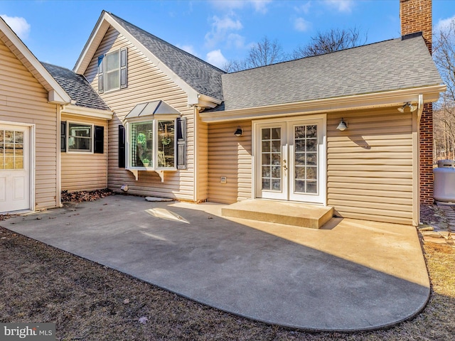 back of house with a patio, french doors, a chimney, and a shingled roof