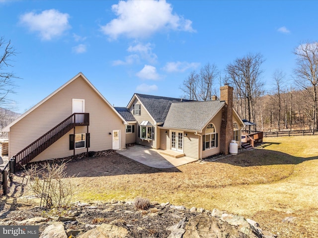 back of property featuring french doors, a yard, a chimney, a shingled roof, and a patio area