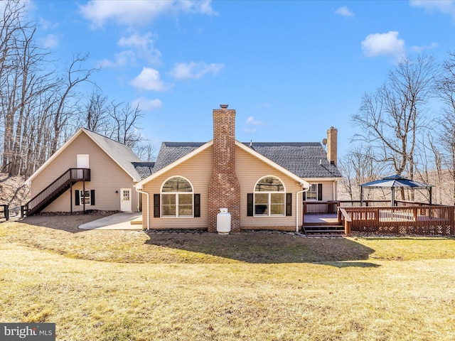 back of property with a deck, a patio, stairs, a yard, and a chimney