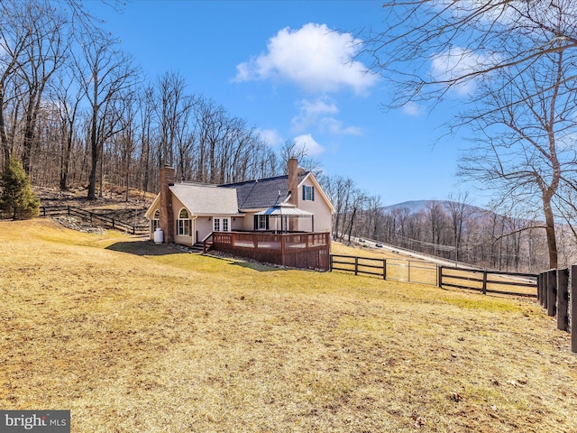 exterior space with a wooden deck, a chimney, a fenced backyard, and a yard