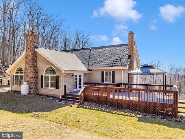 rear view of house with roof with shingles, a yard, a chimney, a gazebo, and a wooden deck