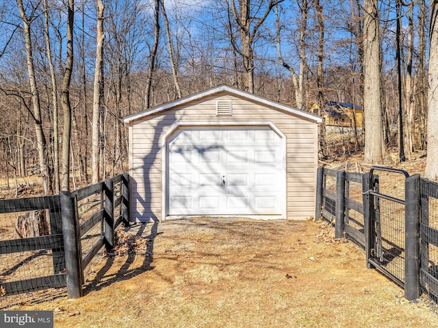 detached garage featuring driveway, a gate, and fence