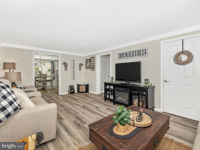 living room with ornamental molding, light wood-type flooring, and baseboards