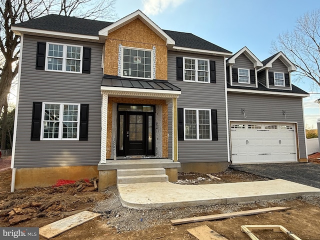 colonial house with metal roof, aphalt driveway, a standing seam roof, and an attached garage