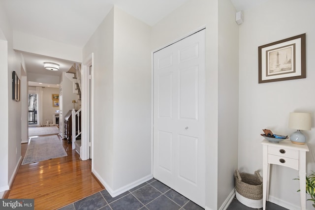 foyer with stairs, baseboards, and dark wood finished floors