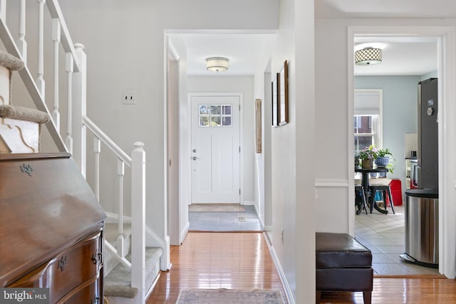 entryway featuring plenty of natural light, stairs, baseboards, and wood finished floors