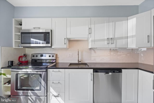 kitchen featuring a sink, white cabinets, appliances with stainless steel finishes, decorative backsplash, and dark countertops