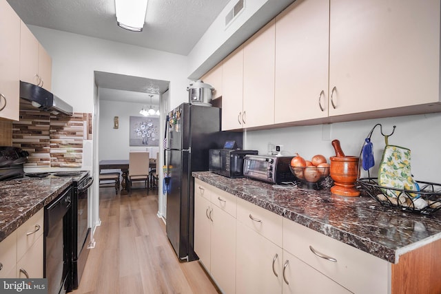 kitchen featuring light wood-style flooring, visible vents, range hood, black appliances, and dark stone countertops