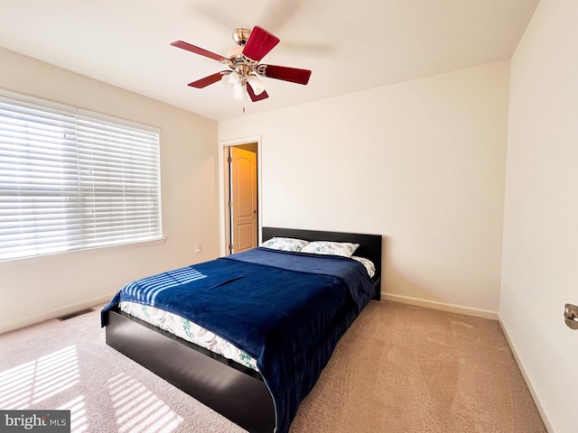 bedroom with light carpet, ceiling fan, visible vents, and baseboards