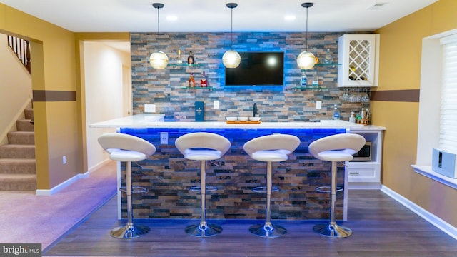 bar with indoor wet bar, decorative light fixtures, visible vents, backsplash, and stairway