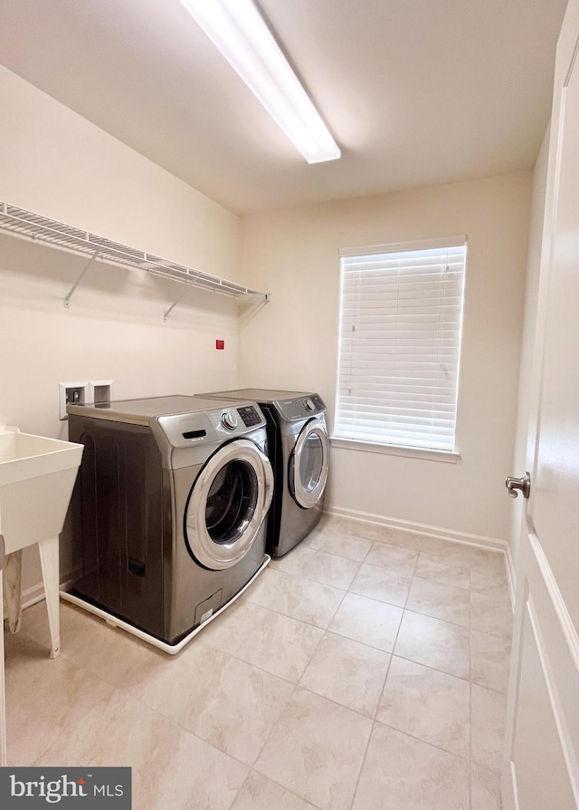 laundry room with light tile patterned floors, laundry area, separate washer and dryer, and baseboards