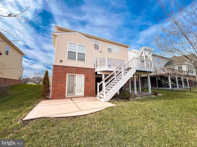 back of property with a lawn, a patio, stairway, a deck, and brick siding