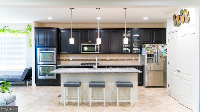 kitchen with stainless steel appliances, a center island with sink, glass insert cabinets, and light stone countertops