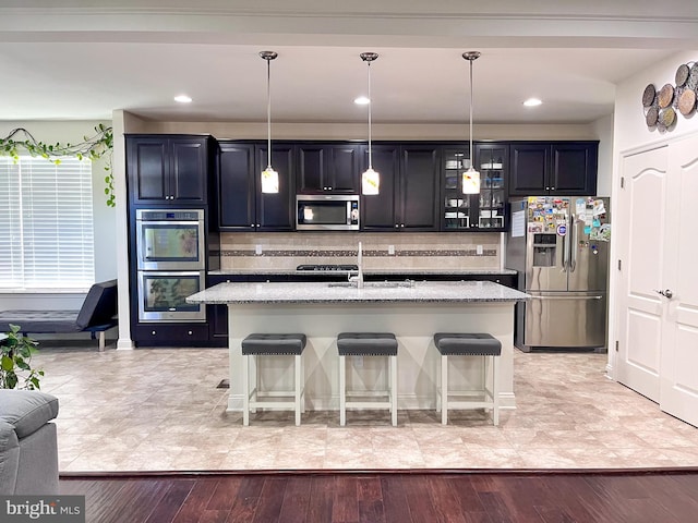 kitchen with appliances with stainless steel finishes, a breakfast bar, decorative light fixtures, and glass insert cabinets