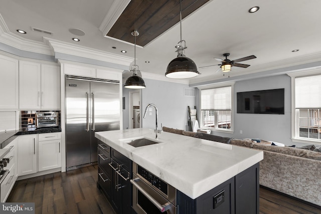 kitchen with open floor plan, stainless steel appliances, a sink, and crown molding