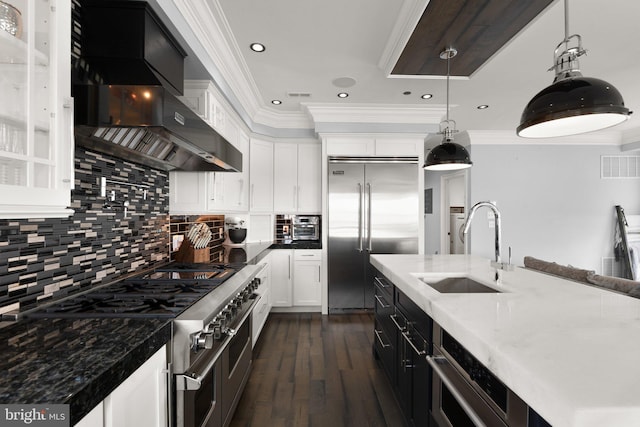 kitchen with visible vents, high quality appliances, range hood, crown molding, and a sink