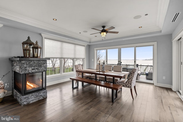 dining space featuring hardwood / wood-style flooring, visible vents, a stone fireplace, and ornamental molding