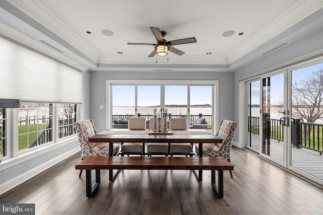 dining room with visible vents, baseboards, ornamental molding, hardwood / wood-style floors, and a raised ceiling