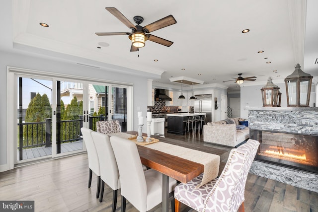 dining area with crown molding, a tray ceiling, and light wood-style floors